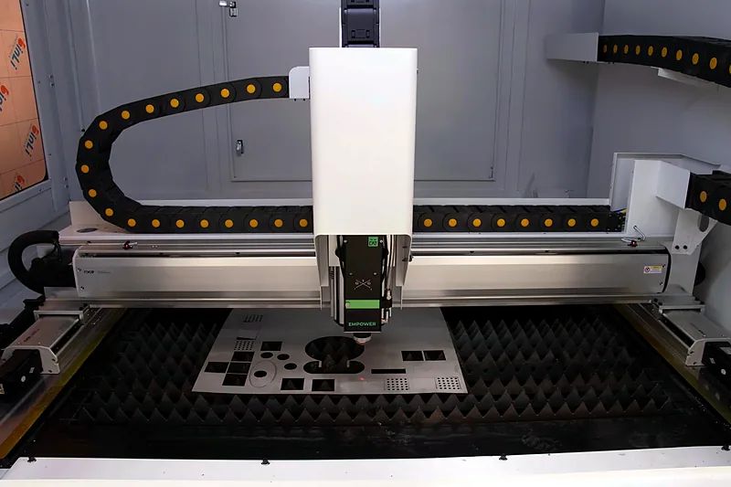 Laser cutting head over a metal cutting bed in the workshop